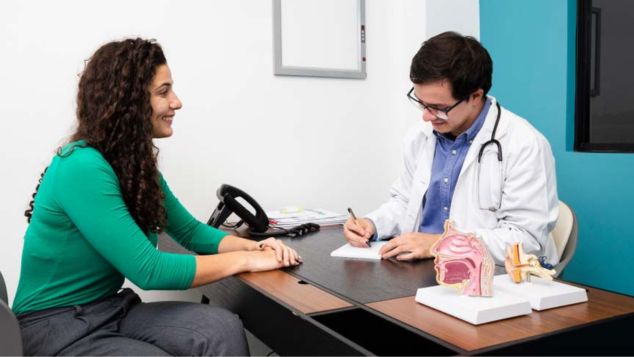 Smiling woman at a doctor's office during her Green Card medical exam.
